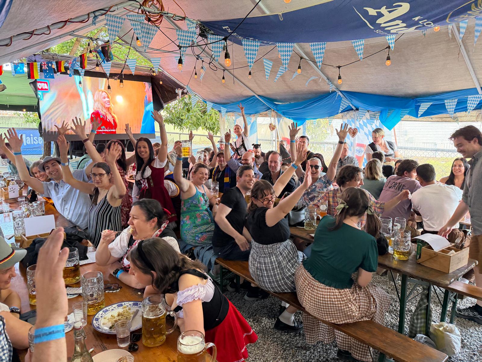 Friends celebrating at German Biergarten Brisbane beneath blue and white bunting